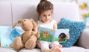 little girl reading a book with a stuffed animal